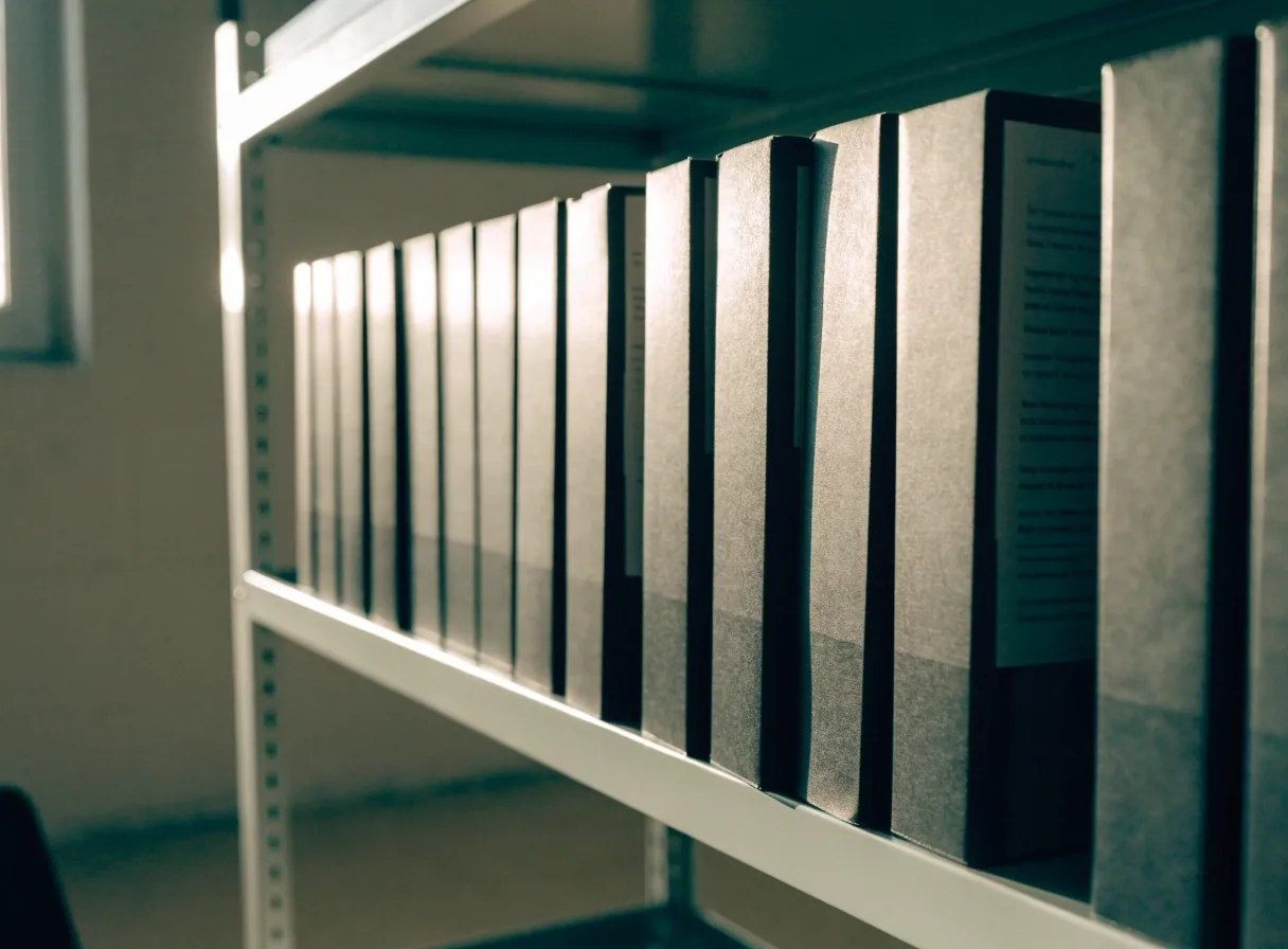 Bound case-study binders lined on a shelf in a consulting practice records room